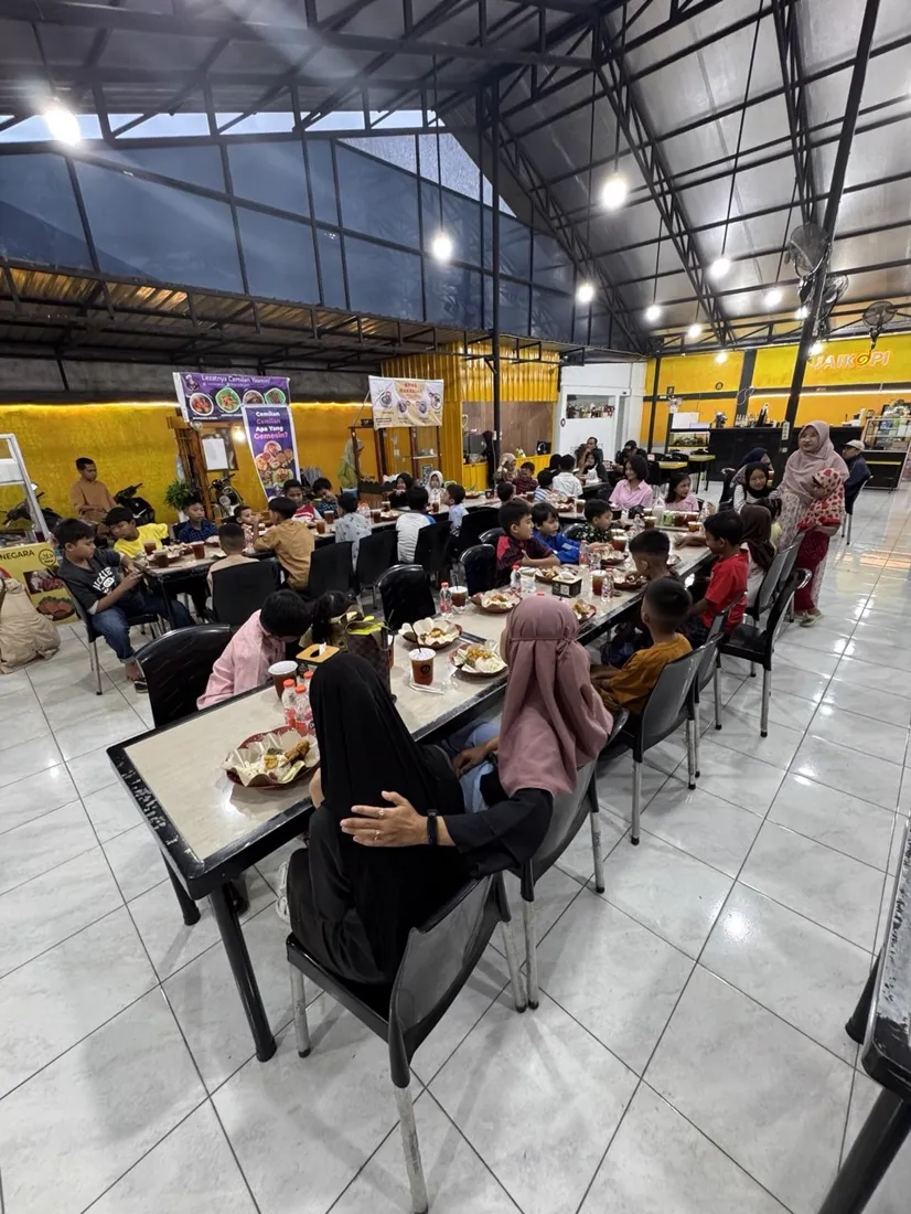 Anak-anak duduk di meja panjang merayakan ulang tahun di Jaikopi
